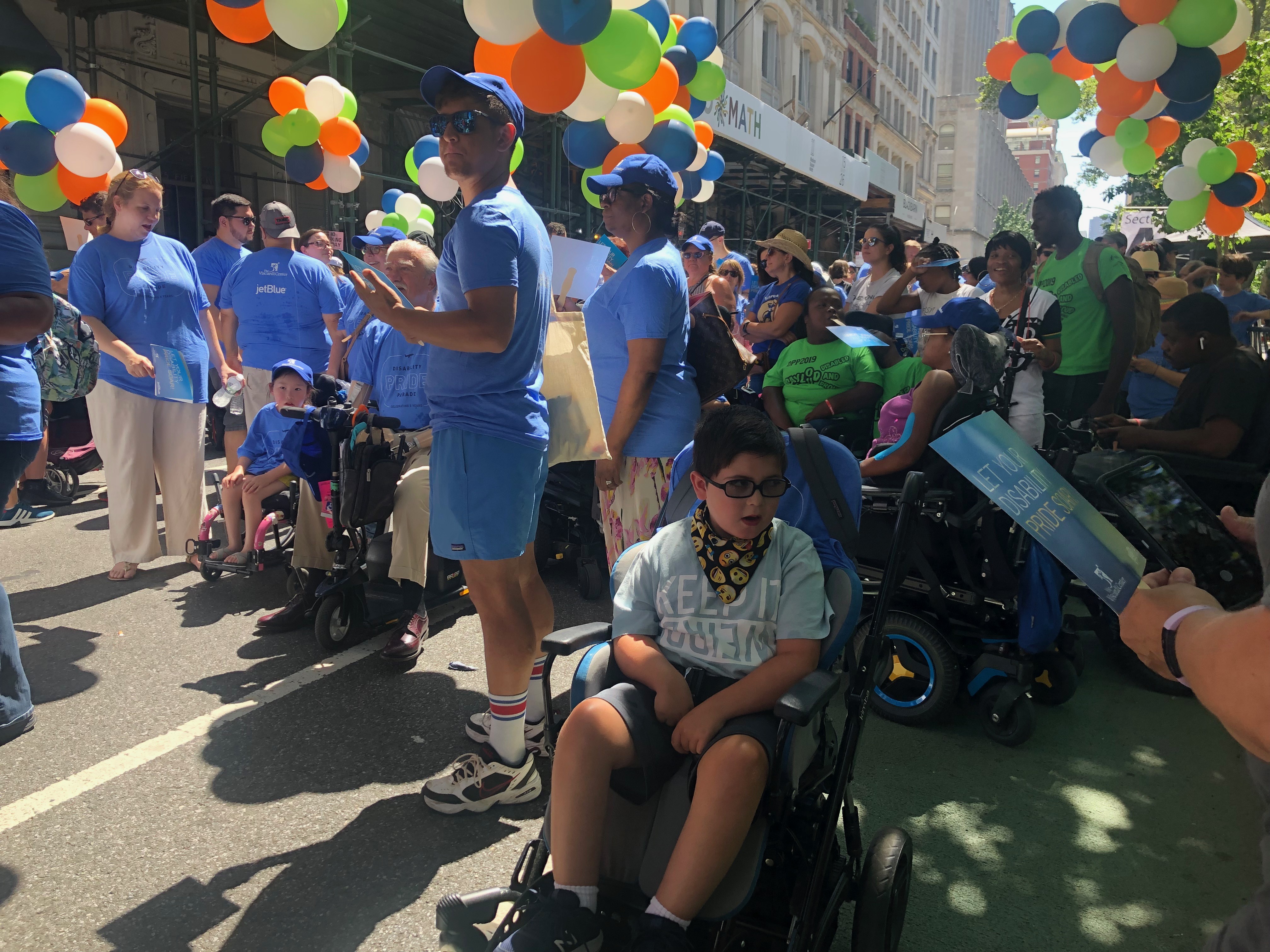 A young boy in mobility device getting ready to march in fifth annual disability pride parade, New York.