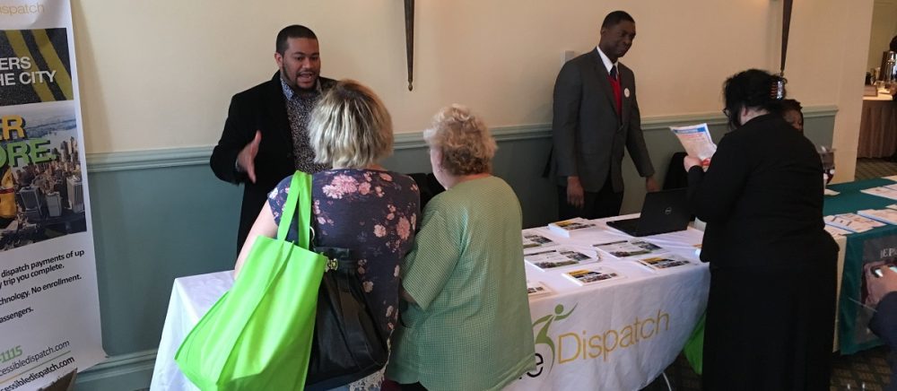 Photo of two members of the Accessible Dispatch outreach team speaking with individuals about the Accessible Dispatch program at a recent event.